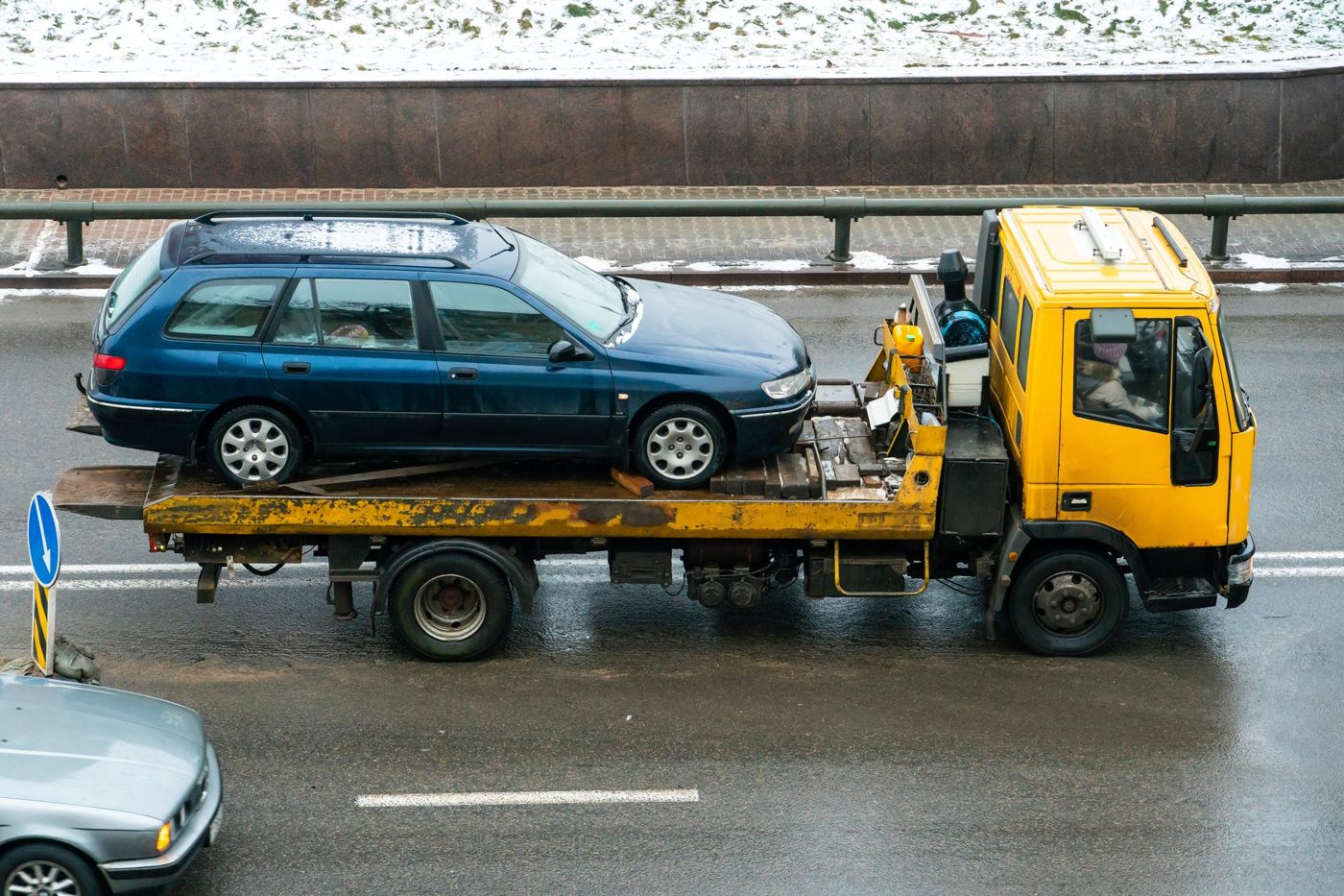 Carroattrezzi con auto caricata su strada bagnata in inverno